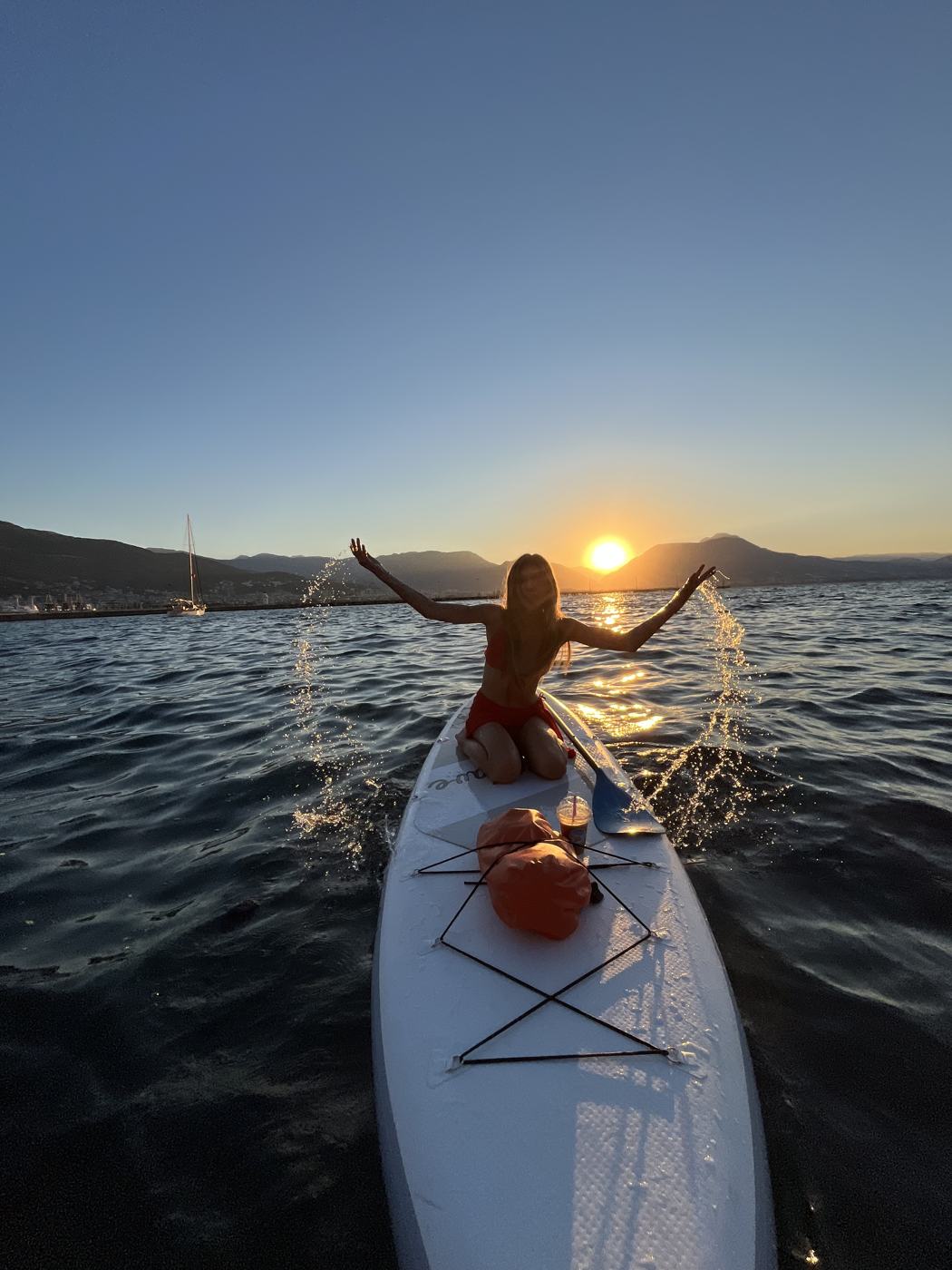 Paddler on a SUP board splashing water toward the rising sun