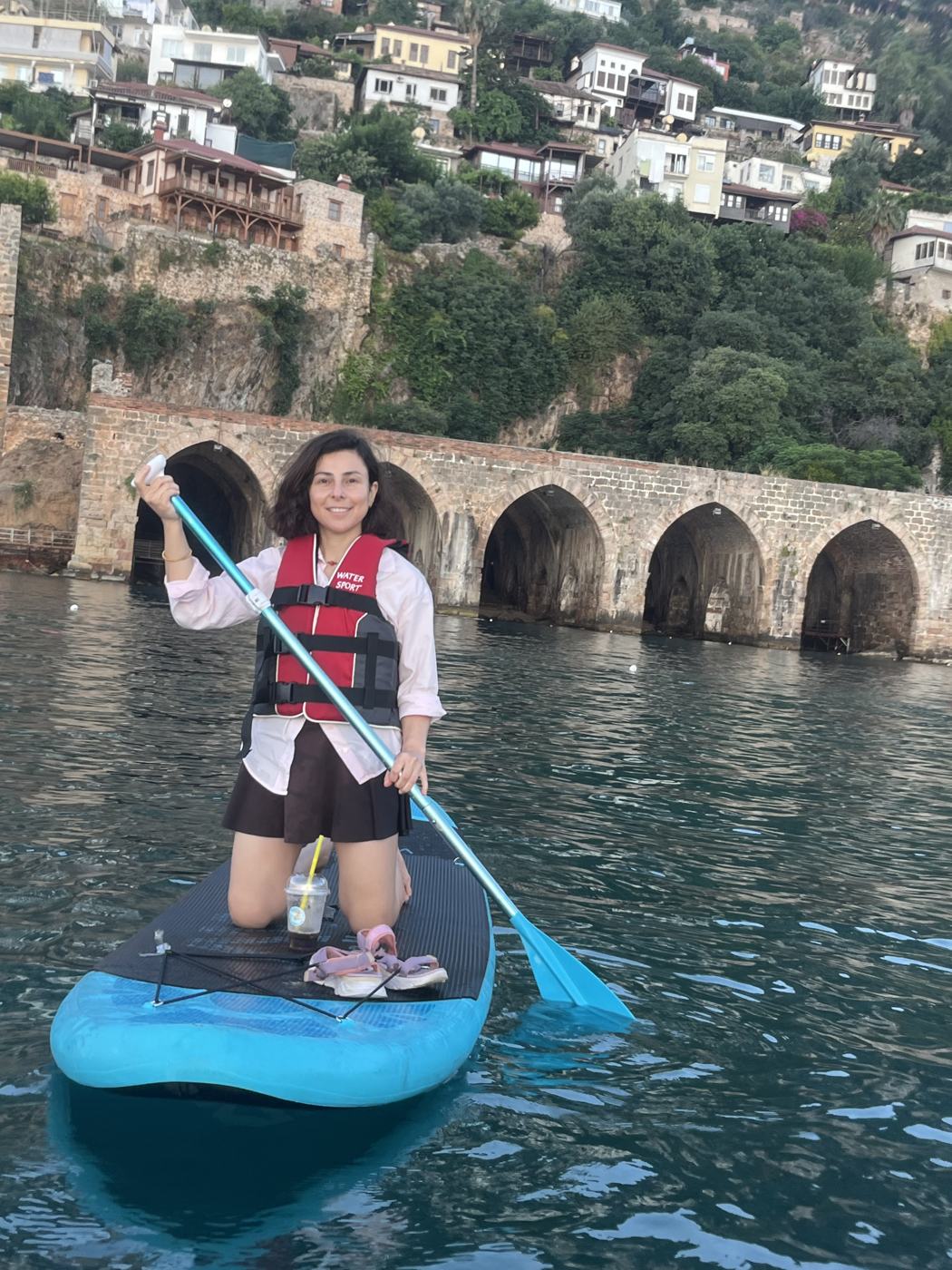 Guest kneeling on a paddle board in front of the Shipyard's stone arches