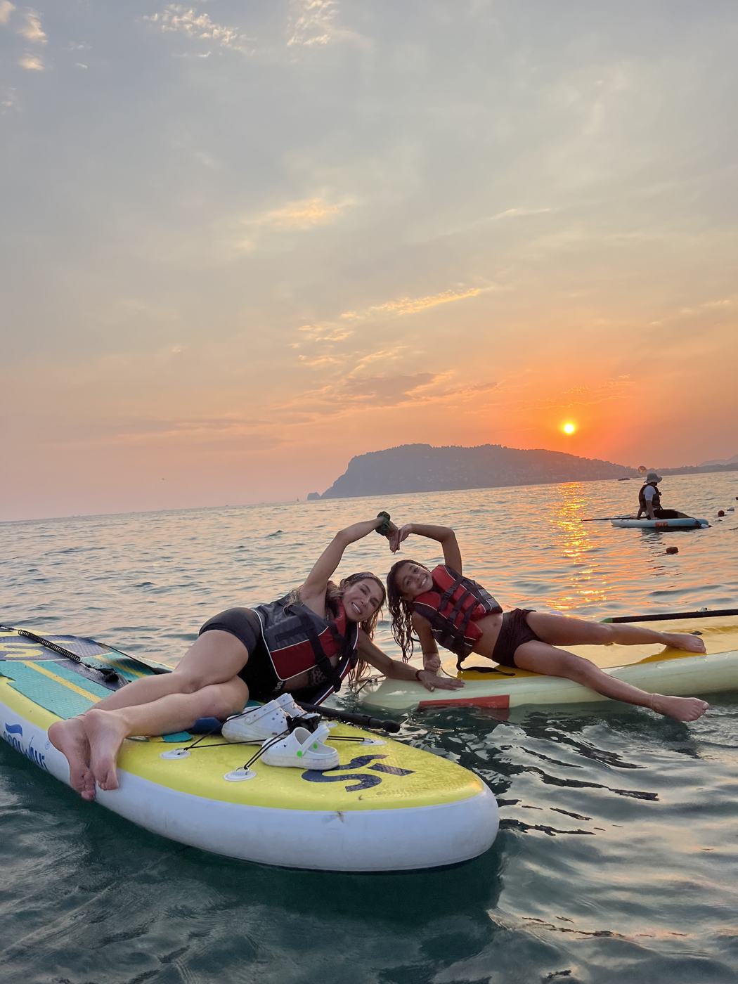 Two paddlers making heart shapes with their hands at sunrise